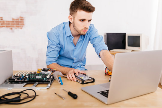 Technician repairing a desktop computer, using laptop