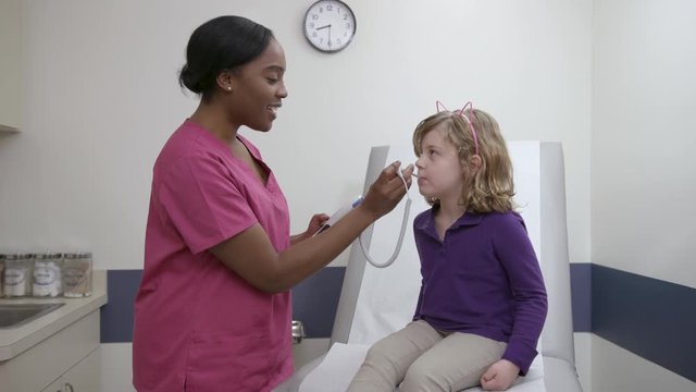 Nurse checks temperature of a pediatric patient in exam room