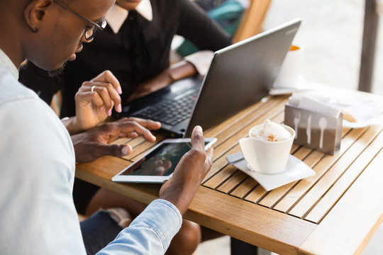 Black African American coworkers doing digital teamwork arround a coffee cup