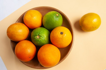 Fruit, orange, lemon, vitamin C source. Clay plate, rustic, handcrafted. Cantaloupe color background. Space for your text.