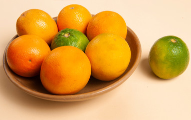 Fruit in clay bowl, rustic, handcrafted.Fruit orange and lemon.Cantaloupe color background.