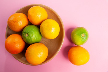 Fruit, orange, lemon, vitamin C source. Clay dish, rustic, handcrafted. Cassis color background. From above. Space for your text.