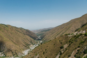 Fototapeta na wymiar A mountain gorge in which a mountain river flows and a road passes. Location near Almaty, Kazakhstan