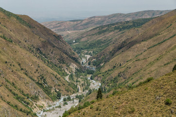 Fototapeta premium A mountain gorge in which a mountain river flows and a road passes. Location near Almaty, Kazakhstan