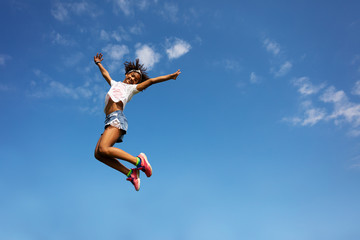 Fototapeta na wymiar Happy girl in high jump over sky with lifted hands