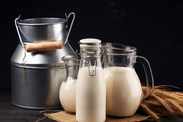 A jug of milk and glass of milk on a wooden black table
