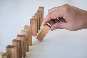 Risk and Strategy in Business, Image of hand gambling placing wooden block on a line of domino,...