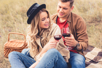 handsome man and attractive woman clinking with wine glasses
