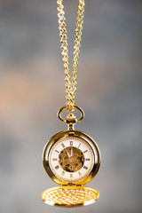 Vintage pocket watch hanging on a chain. Roman numerals on the dial.