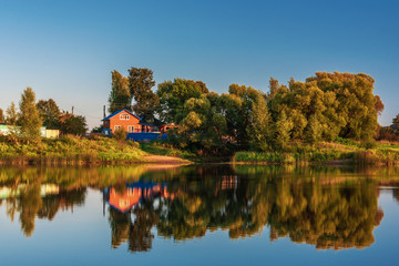 Obraz premium Rural landscape with rural houses, river at sunset