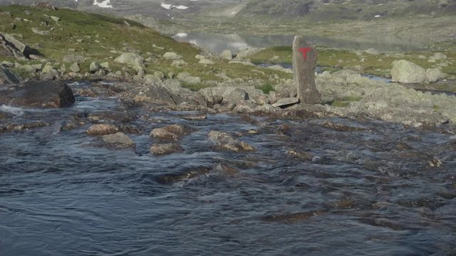 Glacial meltwater river flowing from Hardanger Glacier, Norway hiking trail, tilt up