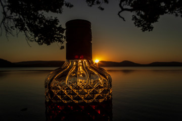 beautiful rum bottle full with rum holding in front of a sunset over Watson Taylors Lake at Crowdy...