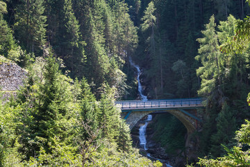 Fototapeta na wymiar Bridge with waterfall in the mountains of the Alps in Tirol, Austria