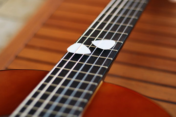 Fototapeta premium Guitar picks on the fingerboard of a brown guitar.