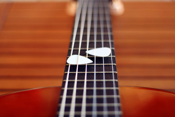 Guitar picks on the fingerboard of a brown guitar.