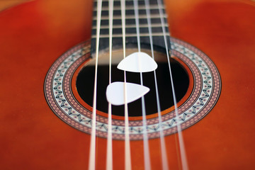 Obraz premium Guitar picks on the fingerboard of a brown guitar.