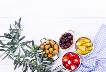 Traditional appetizers, green and red olives from Greek cuisine. Fresh branches of olives. Copy space. Blue checkered tablecloth.