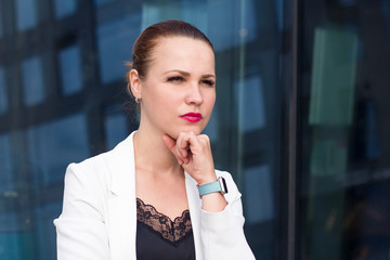 Portrait of confident serious pensive businesswoman outdoor. Thoughtful formal dressed female looking into the distance. Looking aside, put hand prop up on chin.