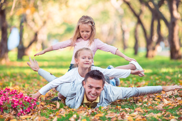 Fototapeta na wymiar Family of dad and kids on beautiful autumn day in the park