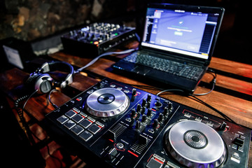 Fototapeta na wymiar DJ plays live set and mixing music on turntable console at stage in the night club. Disc Jokey Hands on a sound mixer station at club party. DJ mixer controller panel for playing music and partying.