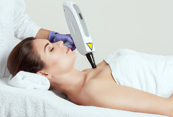 The cosmetologist is making carbon  peeling procedure on the collarbone and face in a beauty salon....