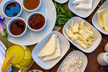 Top view of a breakfast table composed of various cheese, marmalades and orange juice