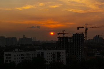 Fototapeta na wymiar Crane and building construction site at sunset