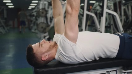 Man performs exercise lifting dumbbells for biceps lying on bench close-up