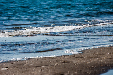 The water of the sea waving to the sand of the beach - photography