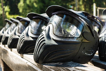 Protective black helmets for paintball lie on a wooden shelf ready for a game, drying the helmet...