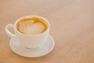 Cup of coffee on a wooden table. White ceramic cup.