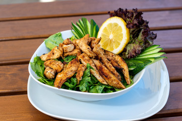 A chicken salad plate with cucumber, lettuce and lemon on the table