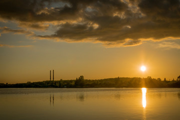a sunset over the Narva reservoir with two chimneys from a power plant.  