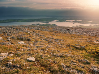 Landscape on a peak with beautiful view on Galway bay in Burren National park, Ireland, Dramatic cloudy sky, Sun flare.