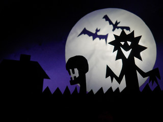 Dark Halloween season background with moon in the background and scary creatures silhouettes. Alien scull, bats, and funny monster.