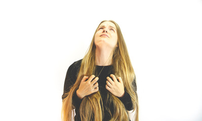 A girl with long blonde hair is in pain, dressed in a black sweatshirt, hands tearing his neck and looking up at the light, on a white background