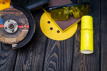 Set of abrasive tools and sandpaper on dark vintage wood background.