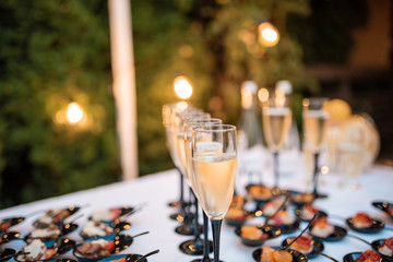 Table with cold snacks on stand and tableware on luxury stand-up