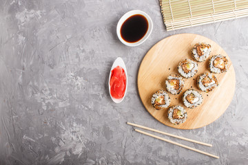 Japanese maki sushi rolls with salmon, sesame, cucumber on wooden board on a gray concrete background. top view, copy space.