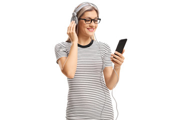 Smiling young woman listneing to music on headphones from a mobile phone