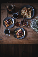 Breakfast table setting on the wooden coffee table. Waffles, coffee time.
