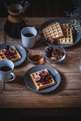 Breakfast table setting on the wooden coffee table. Waffles, coffee time.