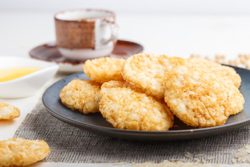 Traditional japanese rice chips cookies with honey and soy sauce on a blue ceramic plate and a cup of coffee on a white wooden background. side view.