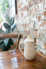 Lavender london fog tea latte with steamed milk and sugar on table in cafe, brick background, copy space