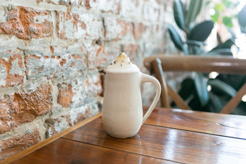 Lavender london fog tea latte with steamed milk and sugar on table in cafe, brick background, copy space