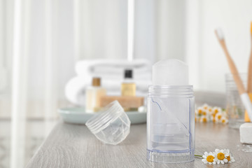 Natural crystal alum deodorant and chamomile flowers on wooden table