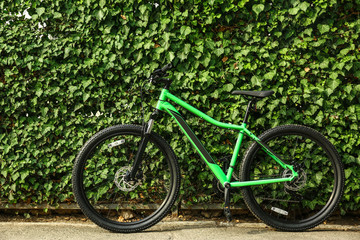 Fototapeta na wymiar Modern bicycle near green hedge outdoors. Healthy lifestyle