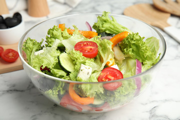 Tasty fresh Greek salad on white marble table, closeup