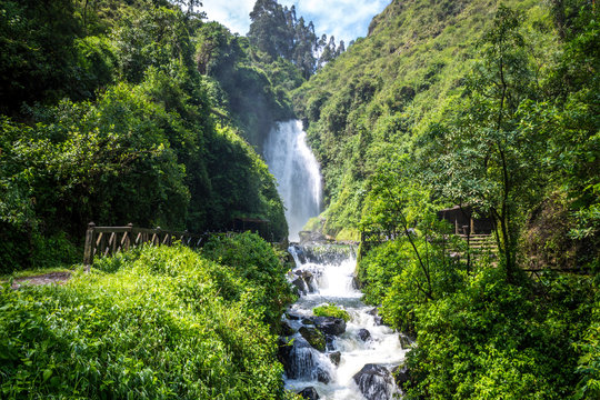 View of Peguche Waterfall in the mountains of Ecuador. It's surrounded by green forest full of vegetation