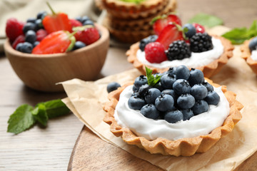 Different berry tarts on wooden table. Delicious pastries